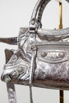 Close up of silver metallic handbag with decorative elements on a white background