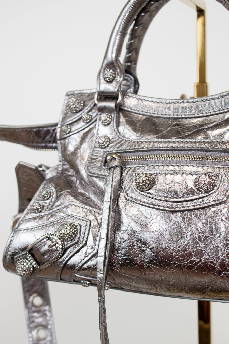 Close up of silver metallic handbag with decorative elements on a white background