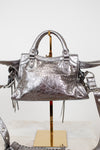 Back view of silver metallic crinkled texture handbag with detailed rhinestone accents on a light background