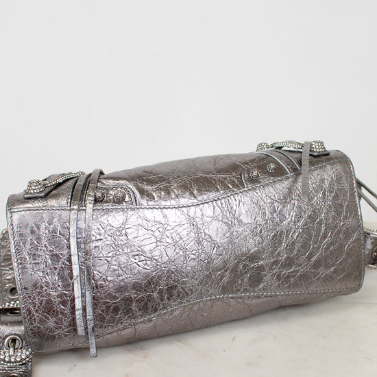 Bottom of silver crinkle metallic handbag with  on a white surface