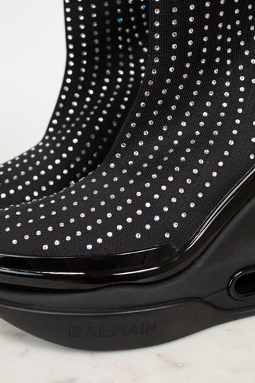 Black ankle boots with silver studs and a brand logo on a light background