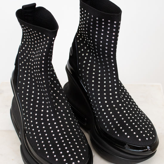 Black ankle boots with silver stud details on a light background