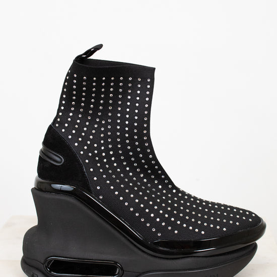 Black studded ankle boot with a wedge sole on a white background