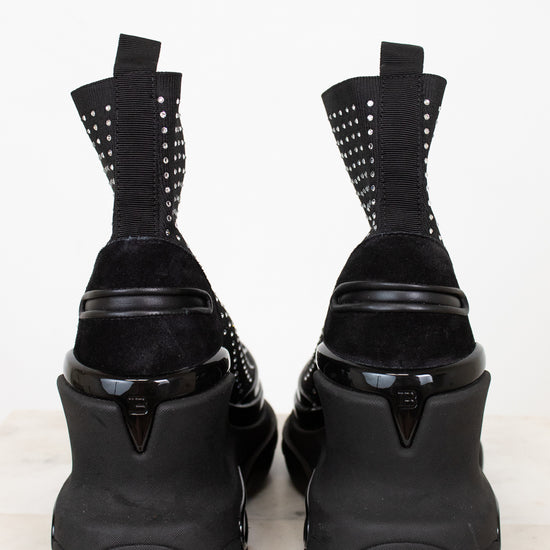 Black high-heeled shoes with silver studded details on a white background