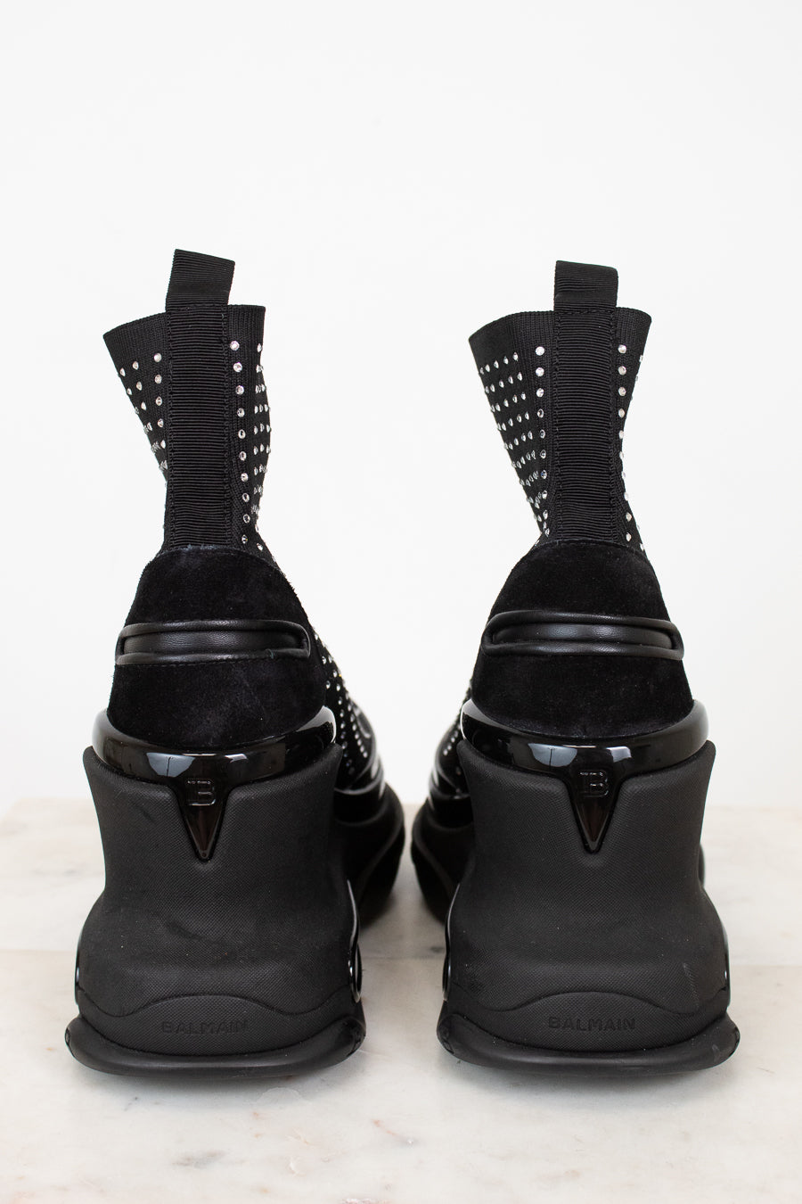 Black high-heeled shoes with silver studded details on a white background