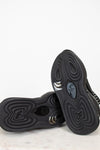 Black boots with athletic unique sole design on a light gray and white background
