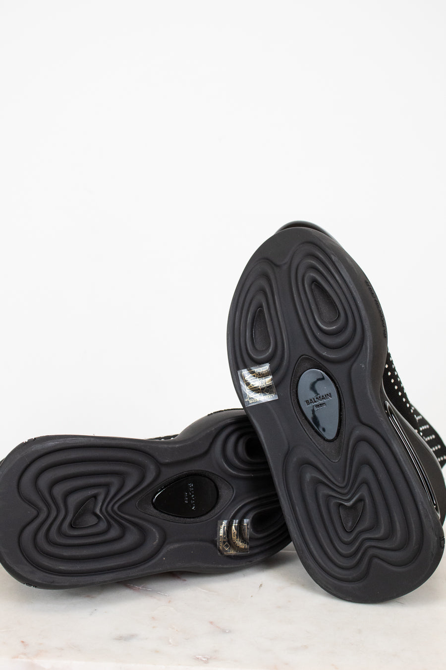 Black boots with athletic unique sole design on a light gray and white background