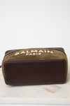 A Balmain Paris zippered pouch in brown suede and dark brown leather, resting on a white marble surface against a white background.
