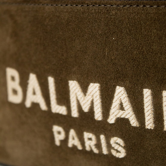 Close-up of a Balmain Paris suede bag in dark brown with a gold zipper and white embroidered logo text.