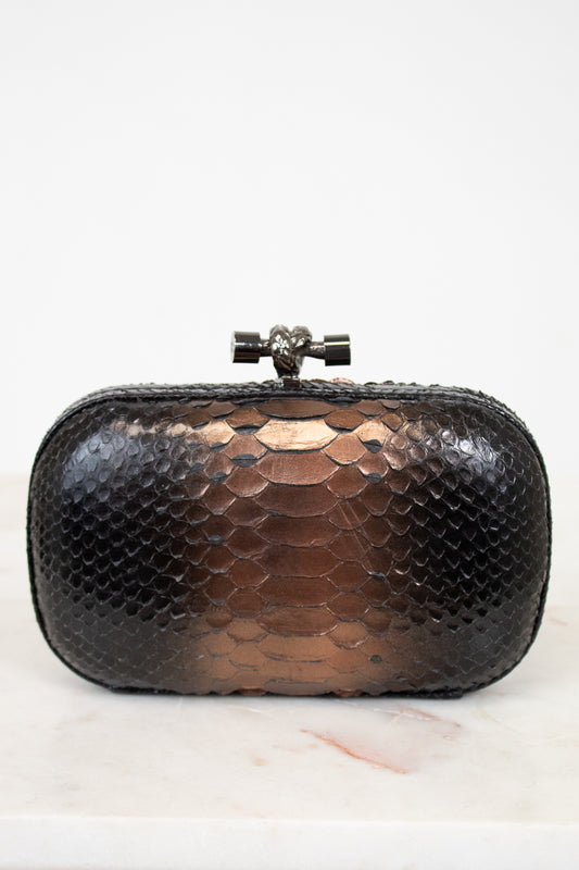 Black and bronze snakeskin patterned clutch bag on a white background