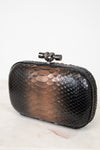 Black metallic clutch bag with a decorative clasp on a white background