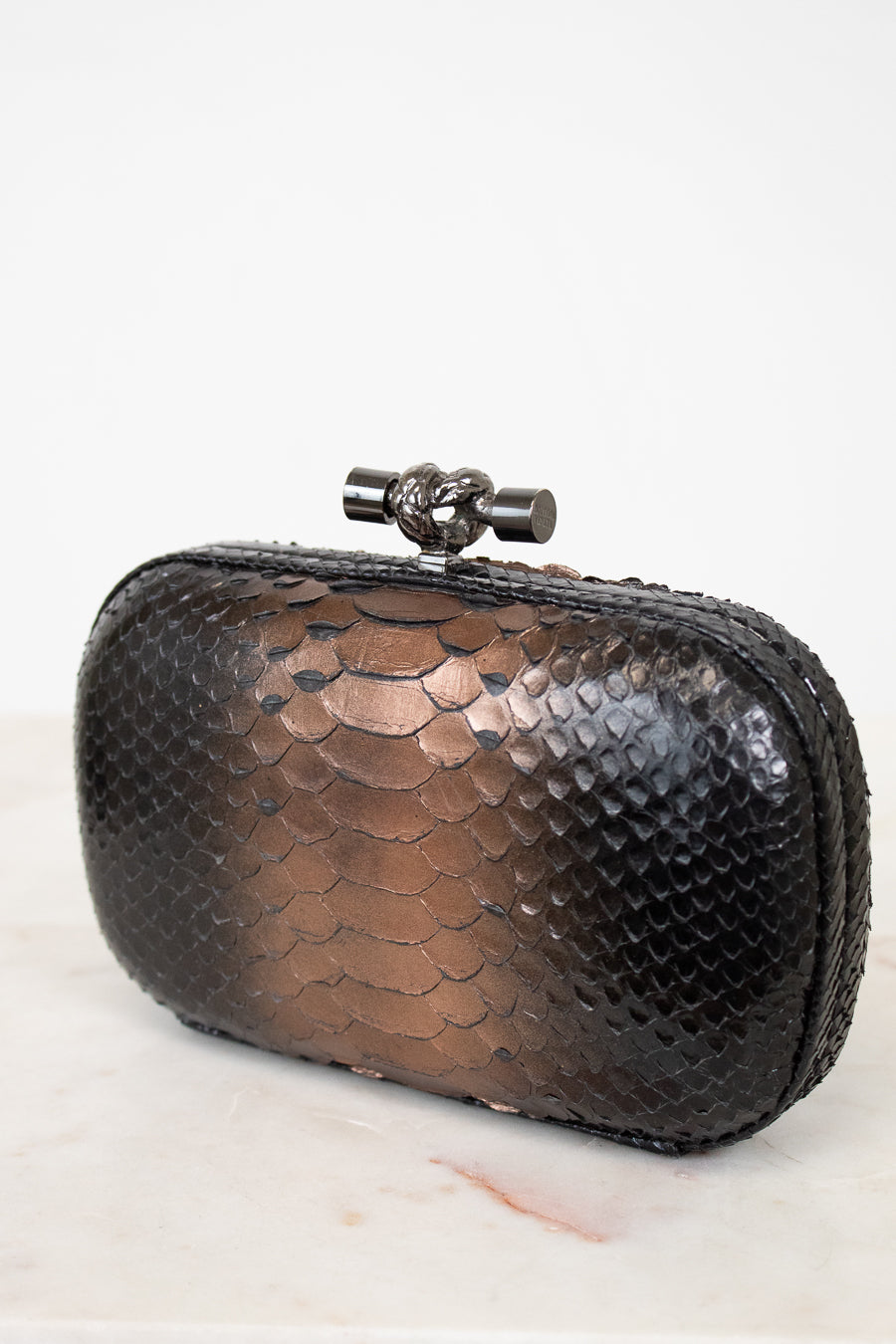 Black metallic clutch bag with a decorative clasp on a white background