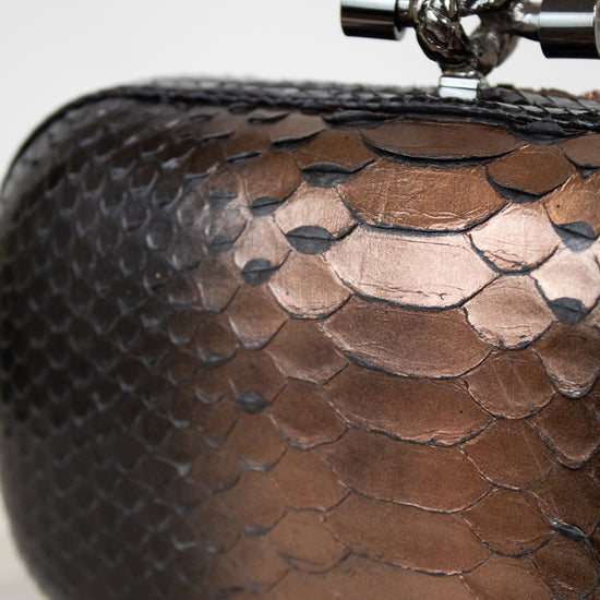 Close-up of a brown textured clutch bag with a metallic clasp on a light background
