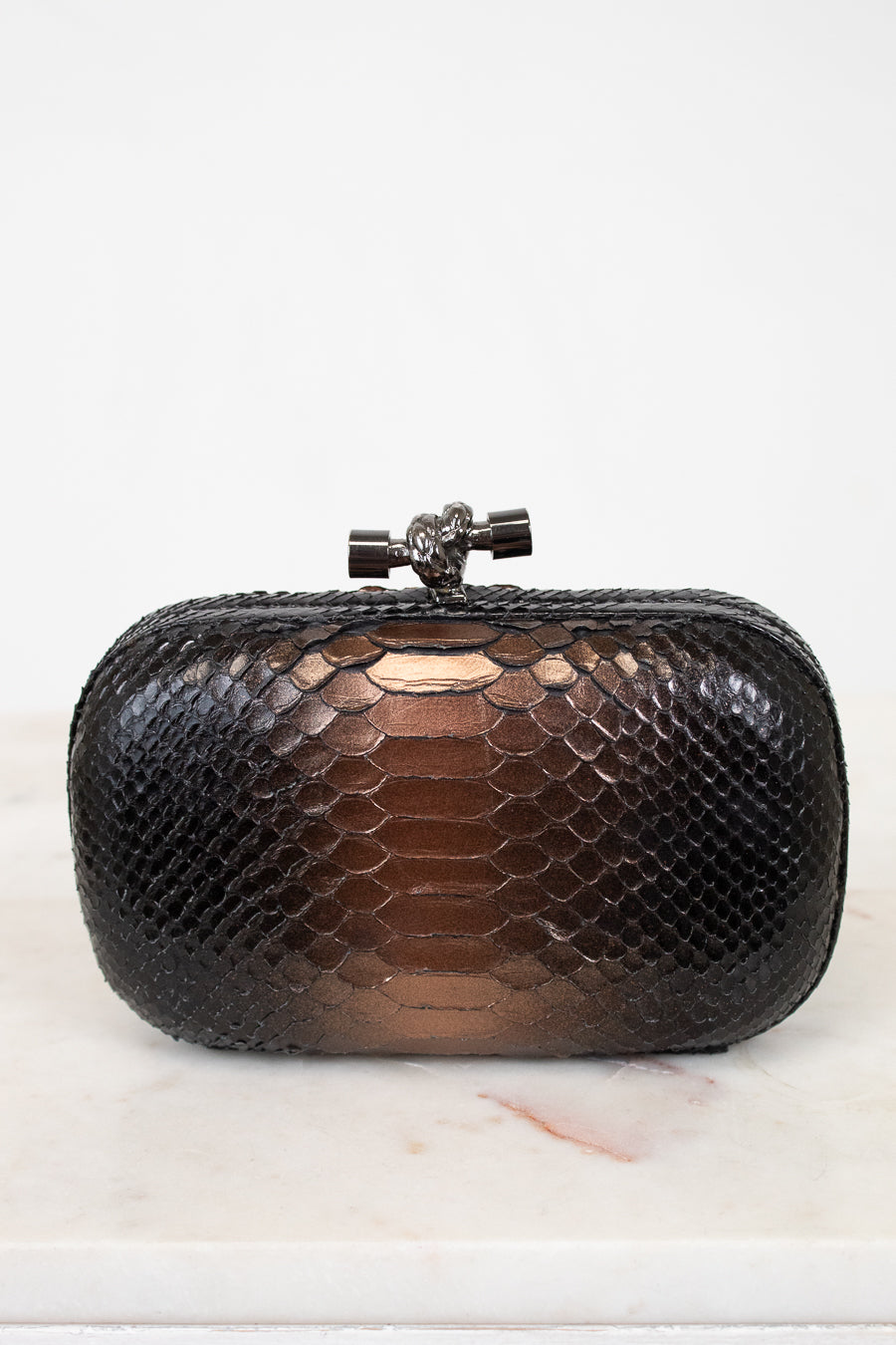 Black snakeskin clutch bag on a light background