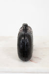 Black textured clutch bag on a white surface