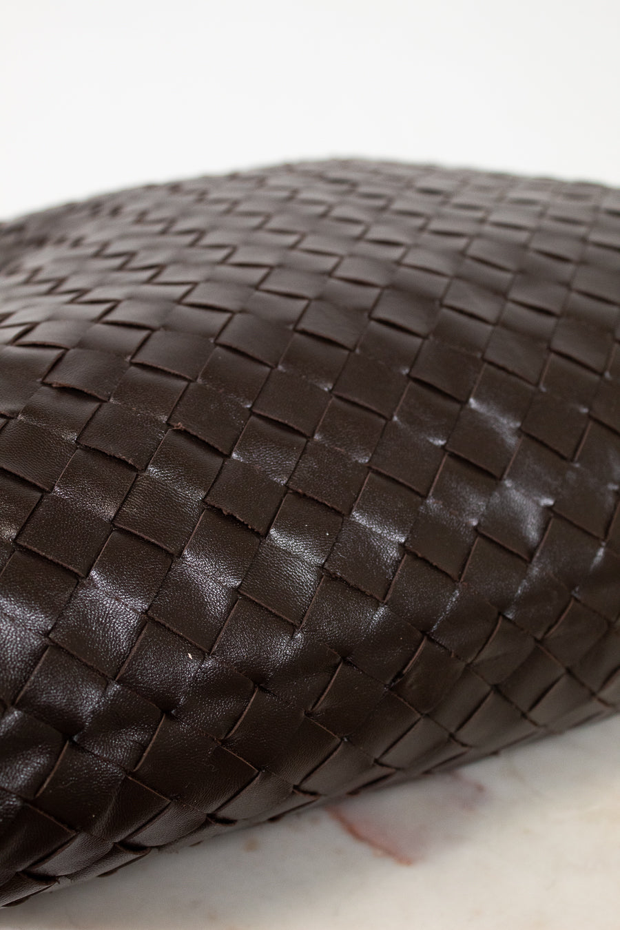 Close-up of a brown woven leather oversized tote on a light background