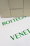 Close-up of a Bottega Veneta product with green text on a white background