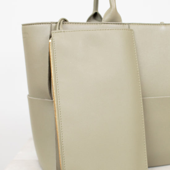 Light green woven handbag on a white background with small matching pouch