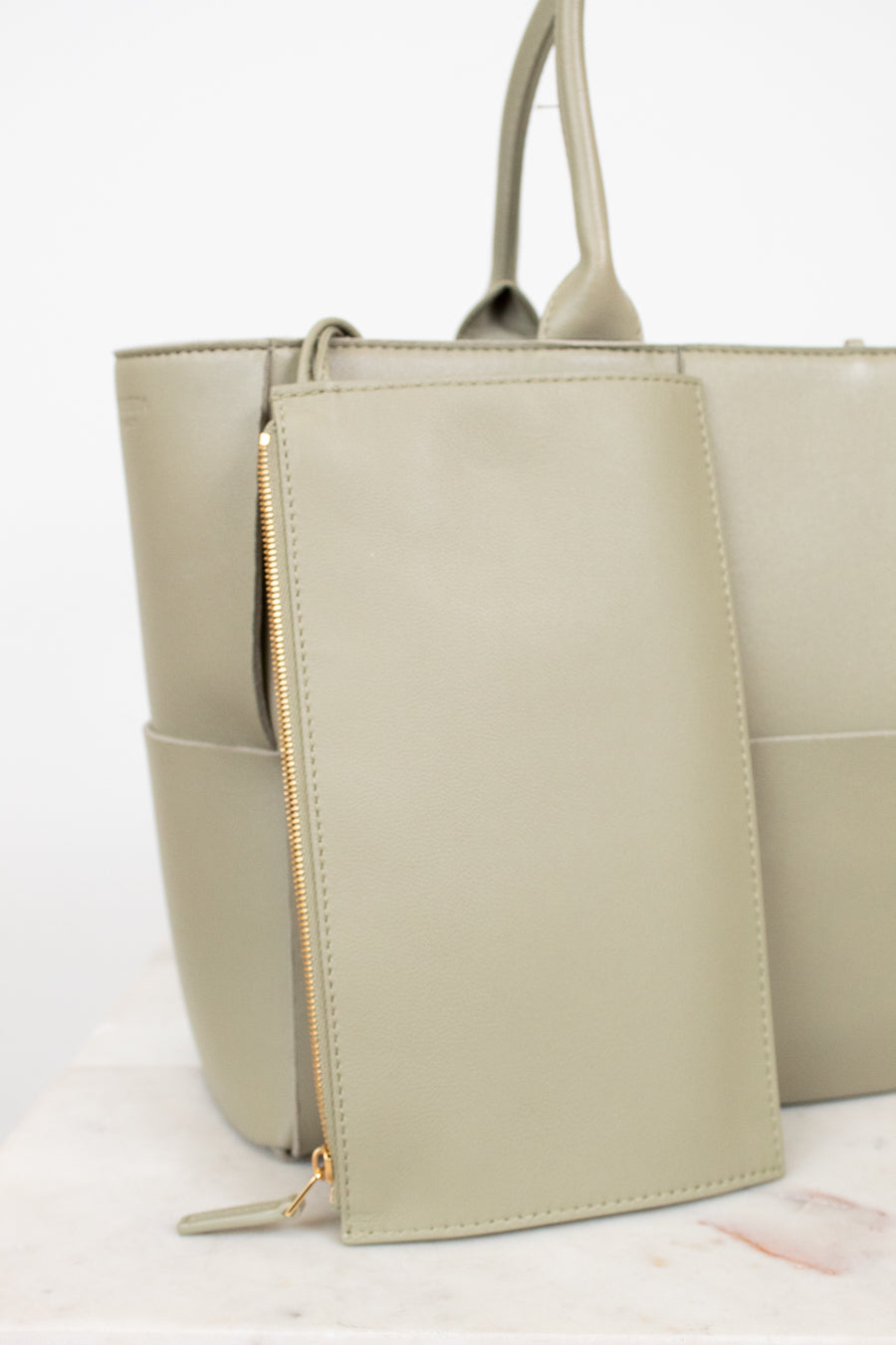 Light green woven handbag on a white background with small matching pouch