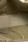 Close-up of a light green leather interior with a visible brand logo.