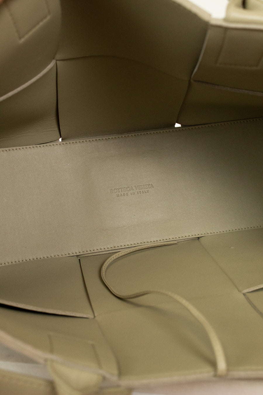 Close-up of a light green leather interior with a visible brand logo.