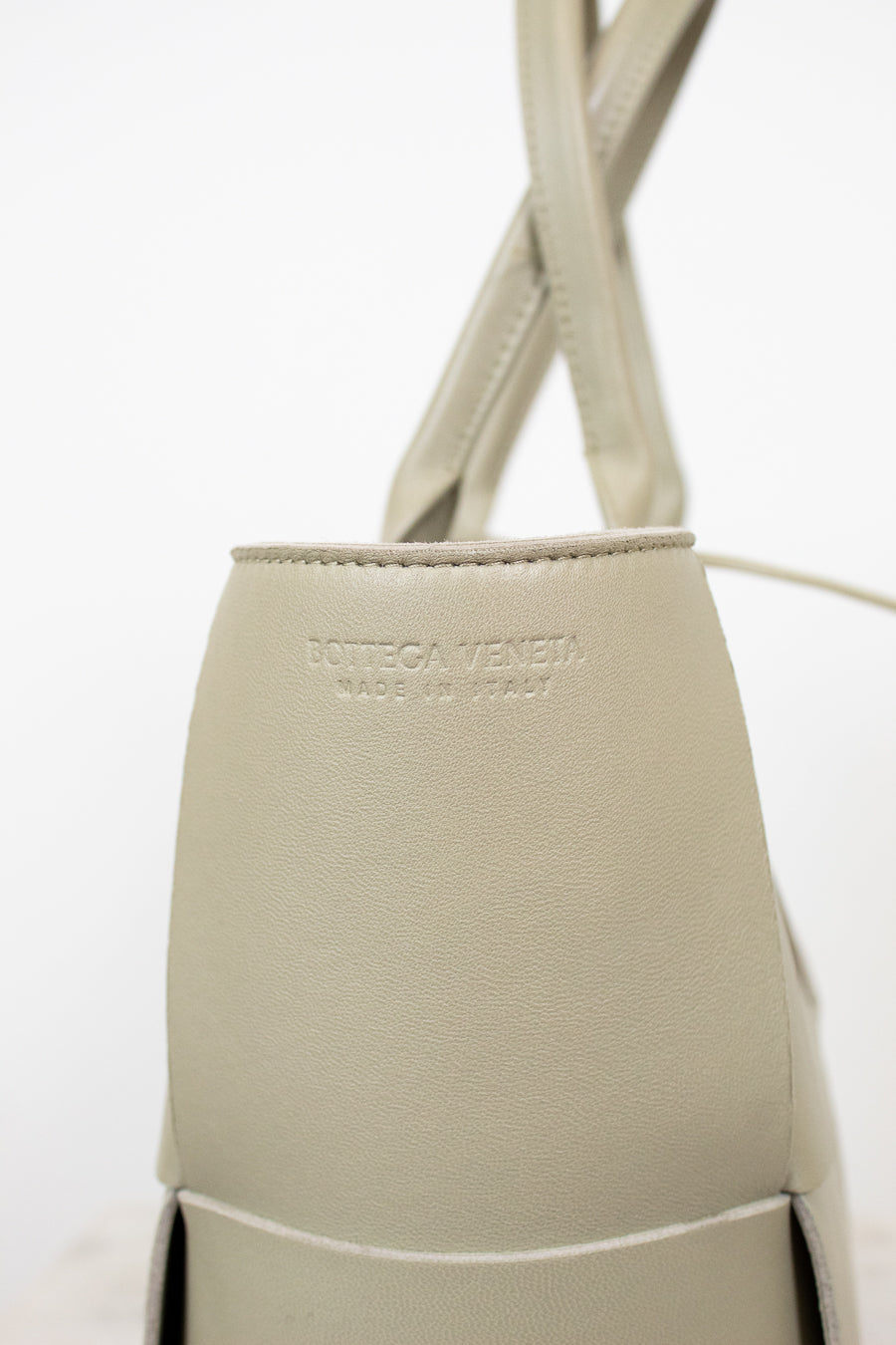 Light green woven handbag on a white background with Bottega Veneta branding stamp