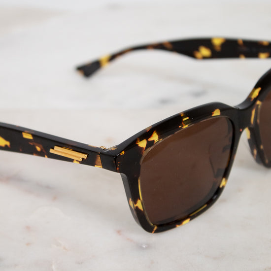 Sunglasses with tortoiseshell frame and brown lenses on a marble surface