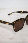 Sunglasses with tortoiseshell frame and brown lenses on a marble surface
