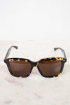 Sunglasses with tortoiseshell frame and brown lenses on a light background