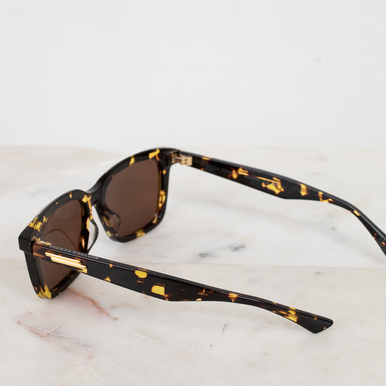 Sunglasses with tortoiseshell frame and brown lenses on a marble surface