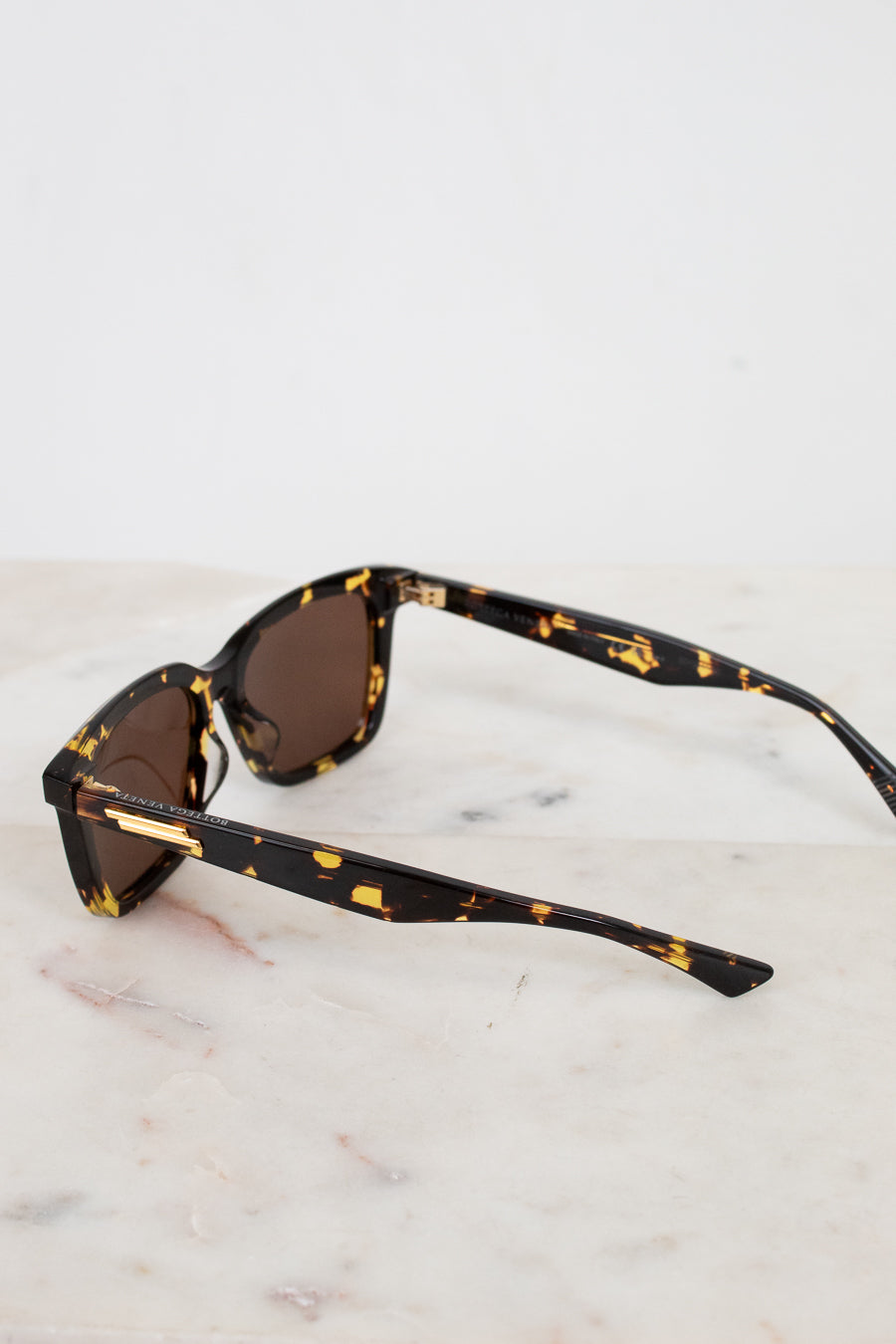 Sunglasses with tortoiseshell frame and brown lenses on a marble surface
