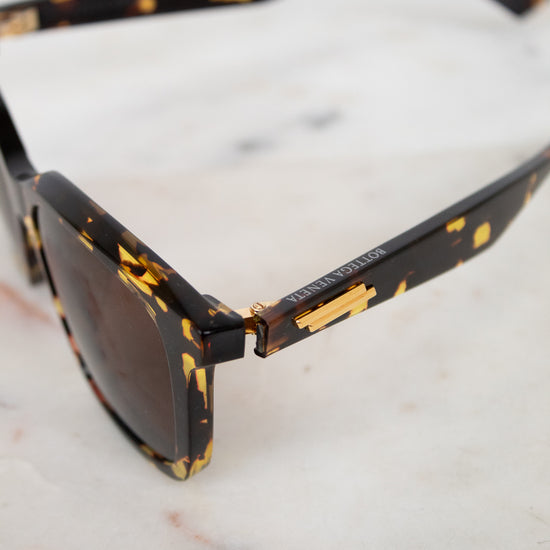 Sunglasses with tortoiseshell frame and dark lenses on a marble surface
