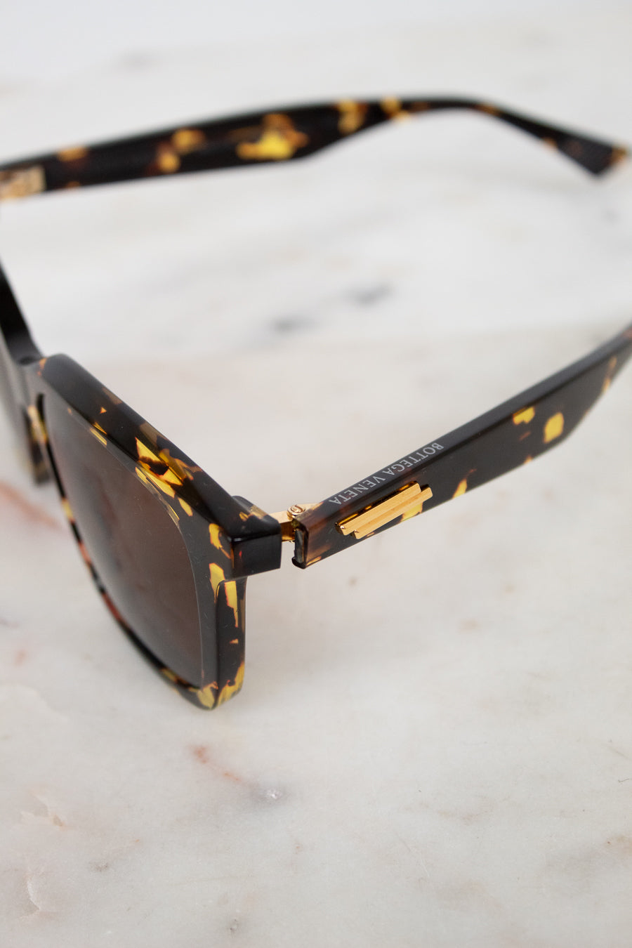 Sunglasses with tortoiseshell frame and dark lenses on a marble surface