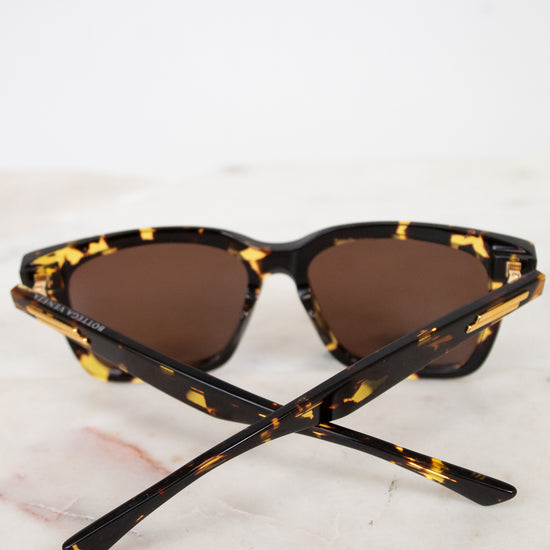 Sunglasses with tortoiseshell frame and brown lenses on a marble surface