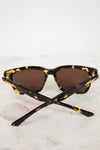 Sunglasses with tortoiseshell frame and brown lenses on a marble surface