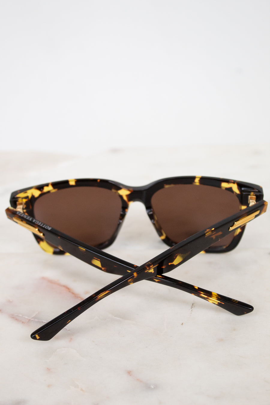 Sunglasses with tortoiseshell frame and brown lenses on a marble surface