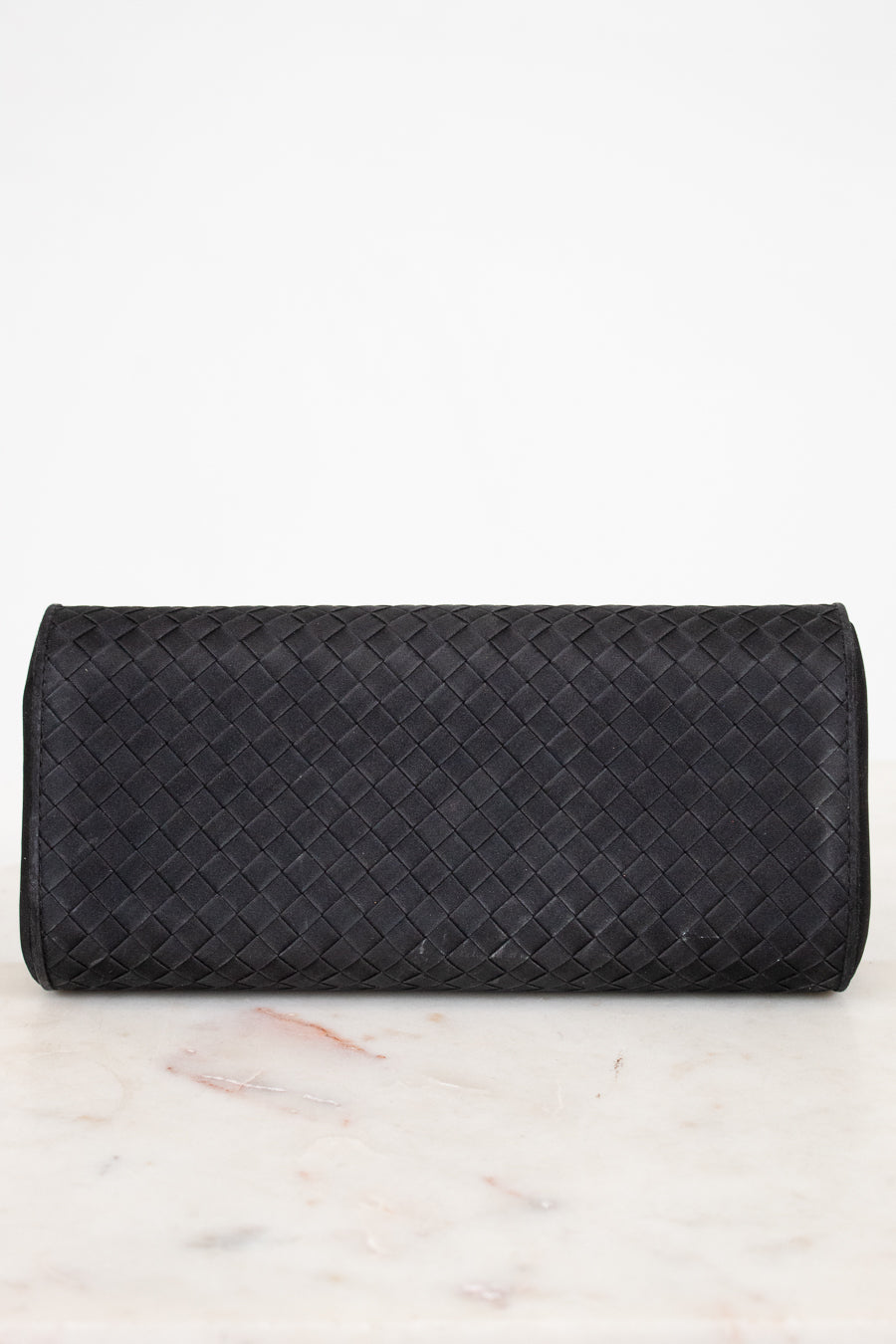 Black woven clutch bag on a marble surface