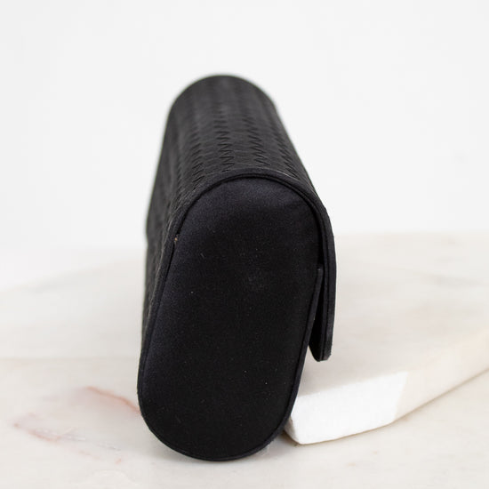 Black rectangular woven clutch on a light marble surface