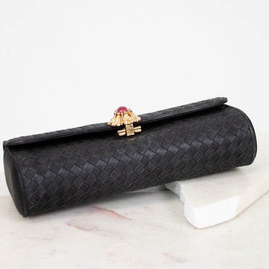 Black clutch bag with a gold clasp on a marble surface