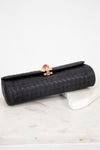 Black clutch bag with a gold clasp on a marble surface