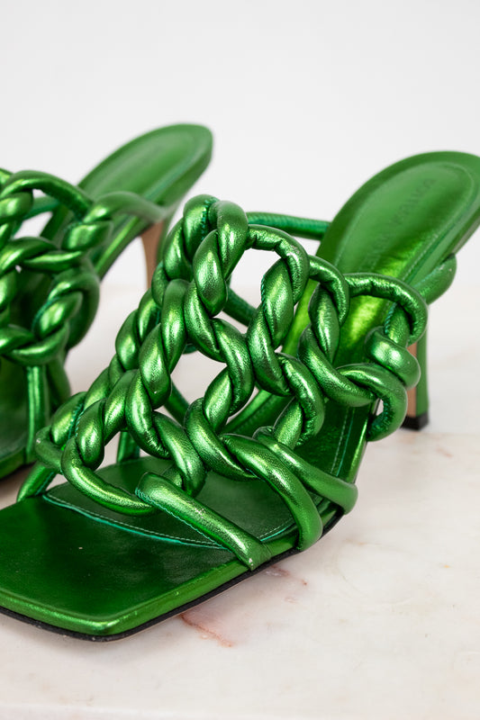 Green metallic sandals with braided design on a light background