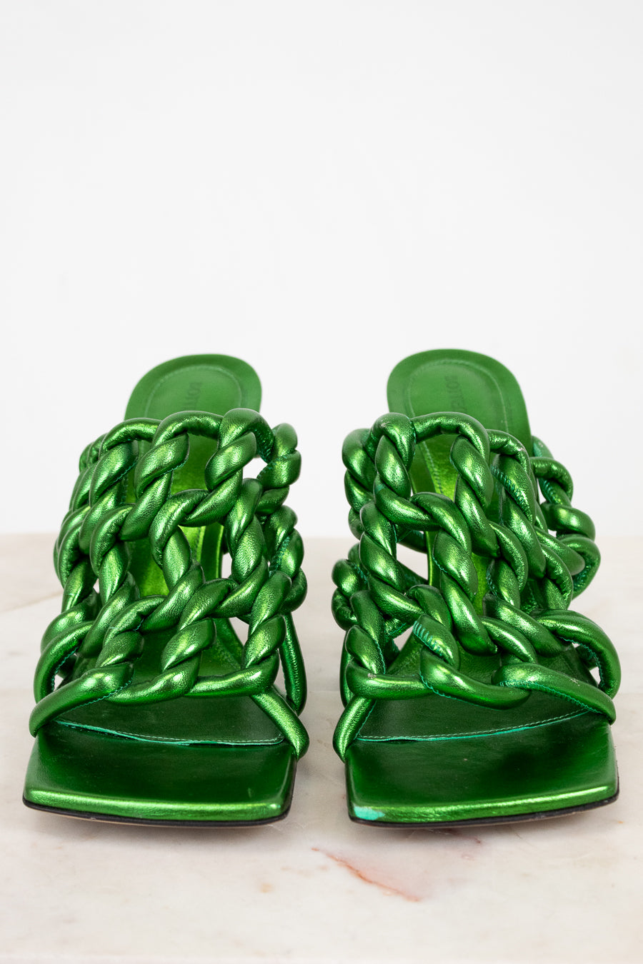 Pair of green metallic sandals with chain-like design on a white background