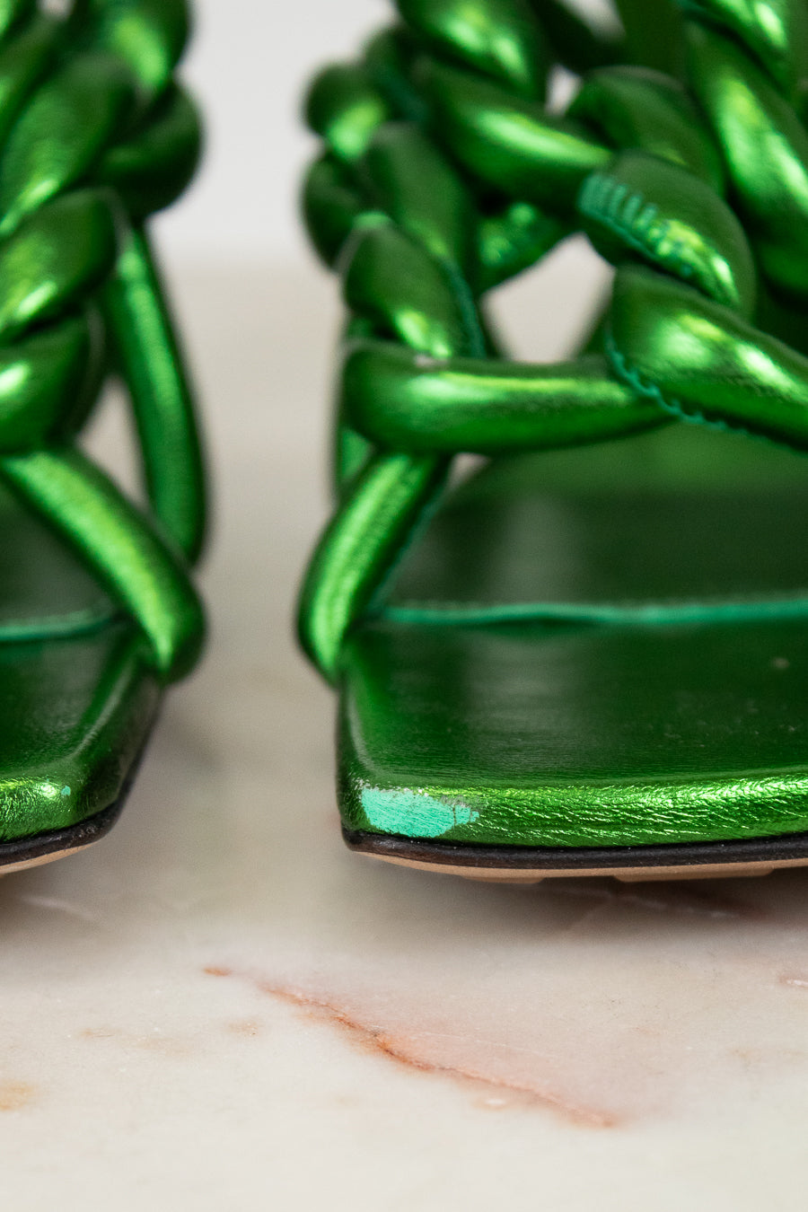 Close-up of green woven sandals on a marble surface