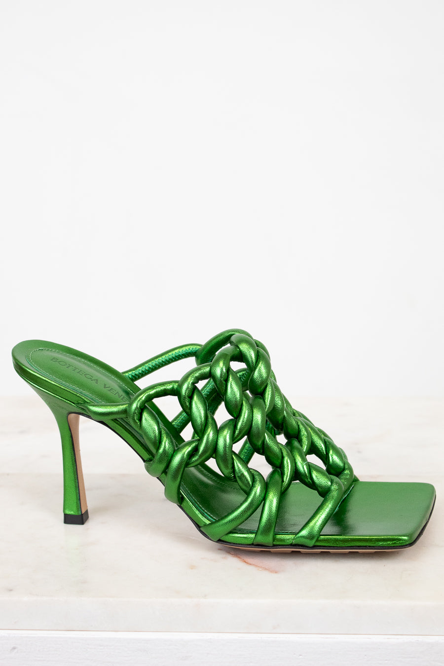 Green high-heeled sandal with chain design on a white background