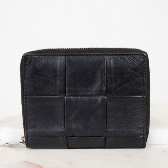 Black quilted wallet on a white marble surface