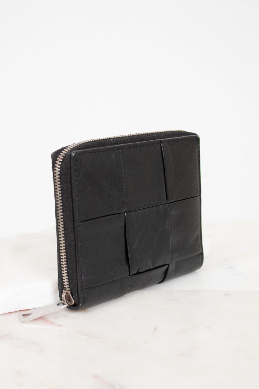 Black leather clutch bag with geometric design on a white background