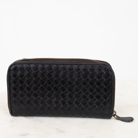 Black quilted wallet on a white marble surface