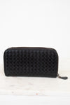 Black quilted wallet on a white marble surface