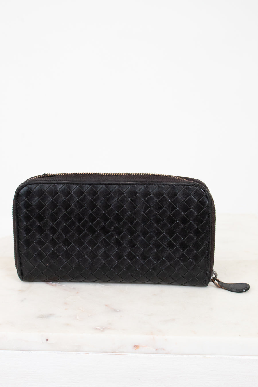Black quilted wallet on a white marble surface