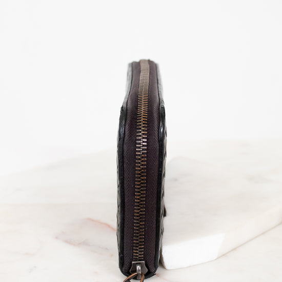 Black leather wallet with zipper on a white marble surface